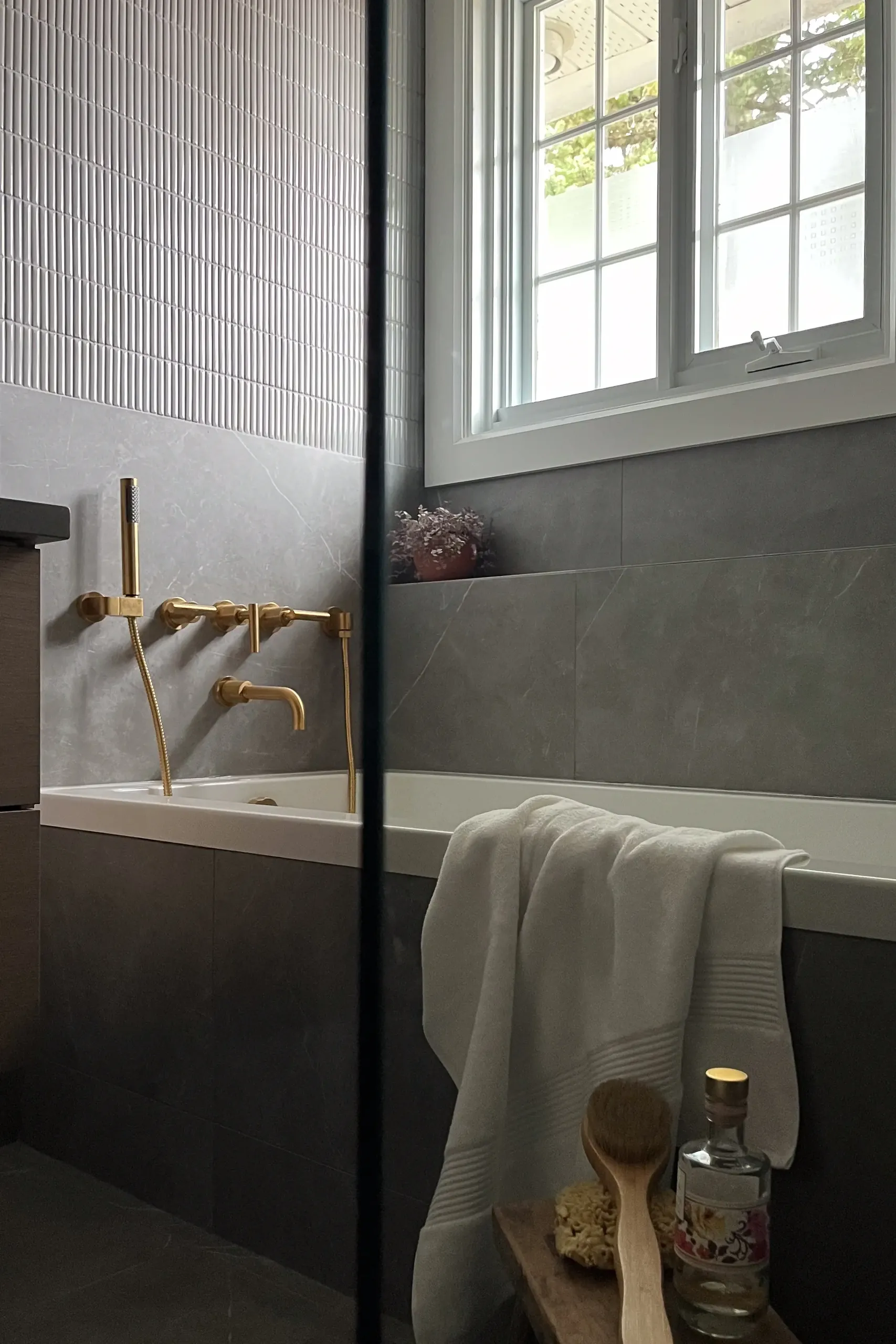 Détail d'applique en laiton sur céramique cannelée — façades de tiroirs en noyer en dessous, salle de bain de Boucherville.