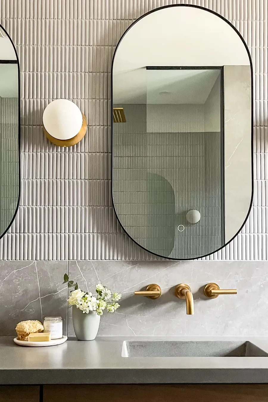 Douche vitrée et banc en bois dans la salle de bain principale de Boucherville — plancher continu en pierre grise.