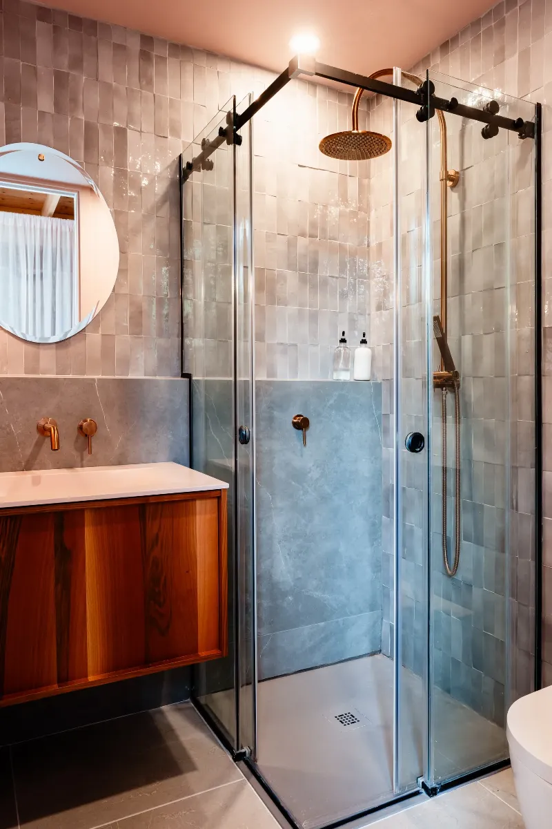 Détail de la salle de bain d'invités — robinetterie en noir mat sur palette de pierre discrète, chalet à Mont-Tremblant.