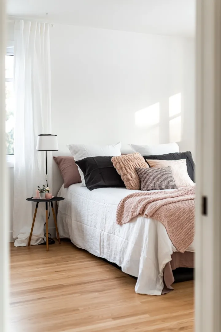 Chambre principale du bungalow de Montréal — lit bas, lin chaleureux, suspension douce près de la fenêtre.