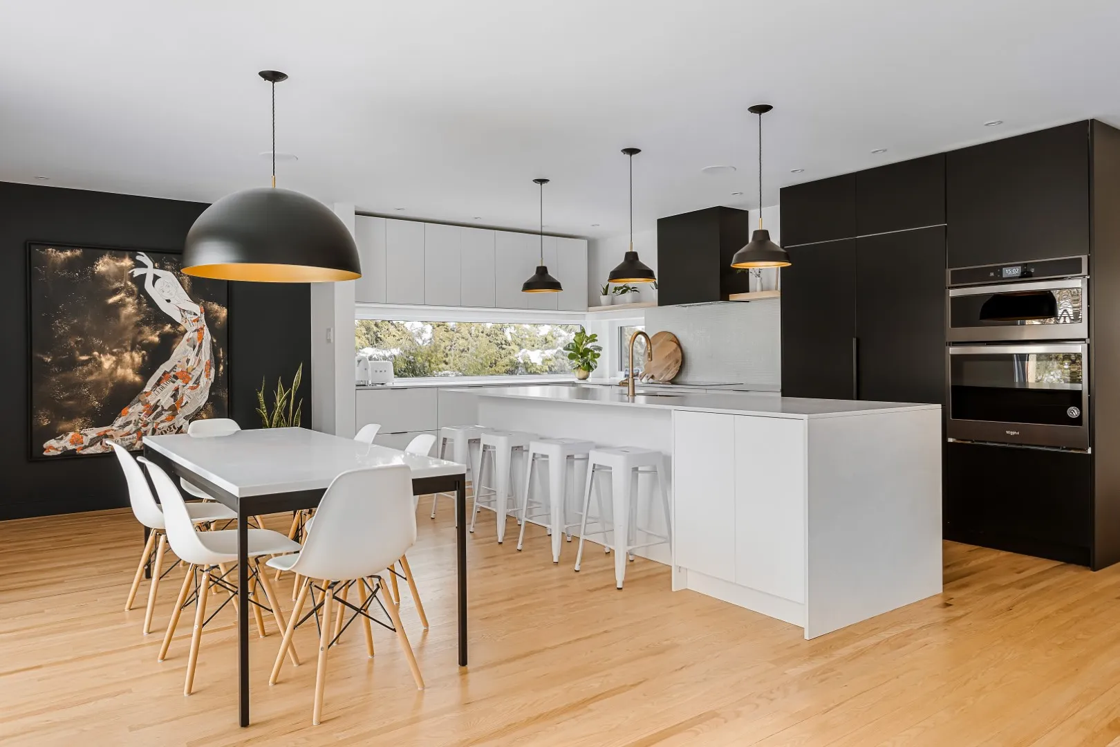 Cuisine et salle à manger à aire ouverte sous une paire de suspensions sculpturales — rénovation du bungalow de Montréal.