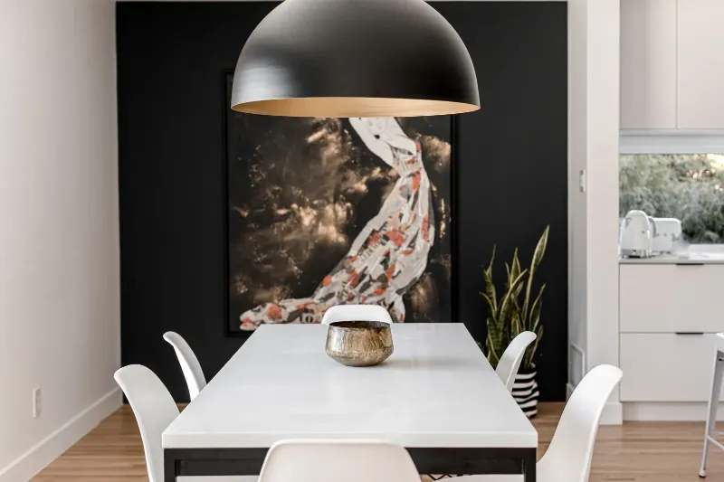 Salle à manger cadrée par un pan de mur anthracite et une œuvre figurative — bungalow de Montréal.