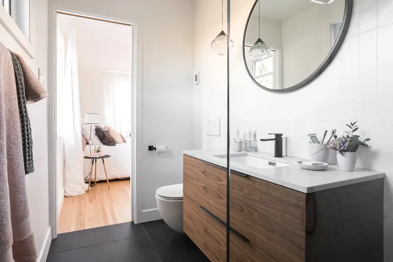 Vue large de la salle de bain principale — longue vanité en noyer et douche à l'italienne, bungalow de Montréal.