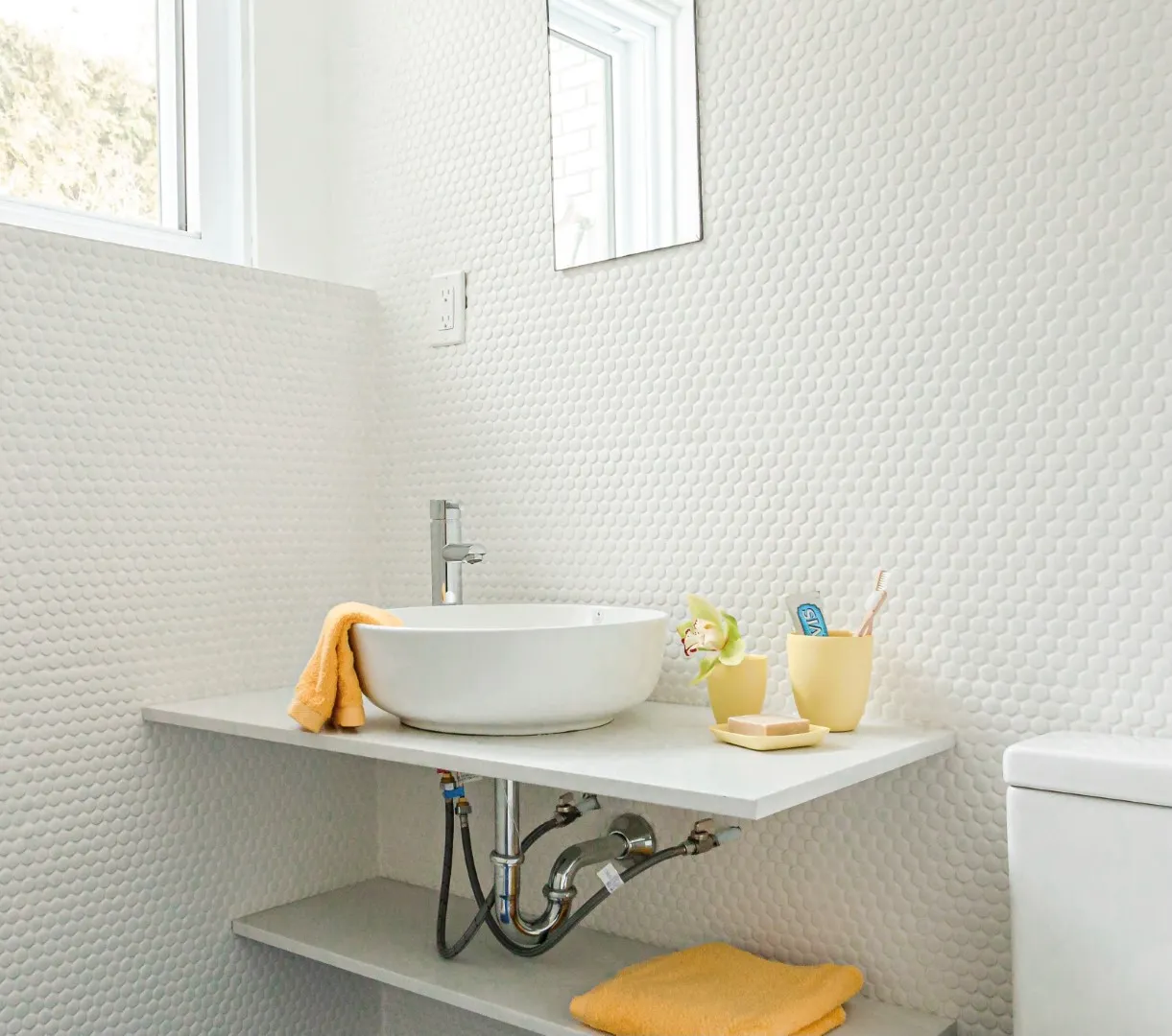 Salle de bain du sous-sol dans la rénovation du bungalow de Montréal — compacte, tapissée de pierre, à l'éclairage chaleureux.