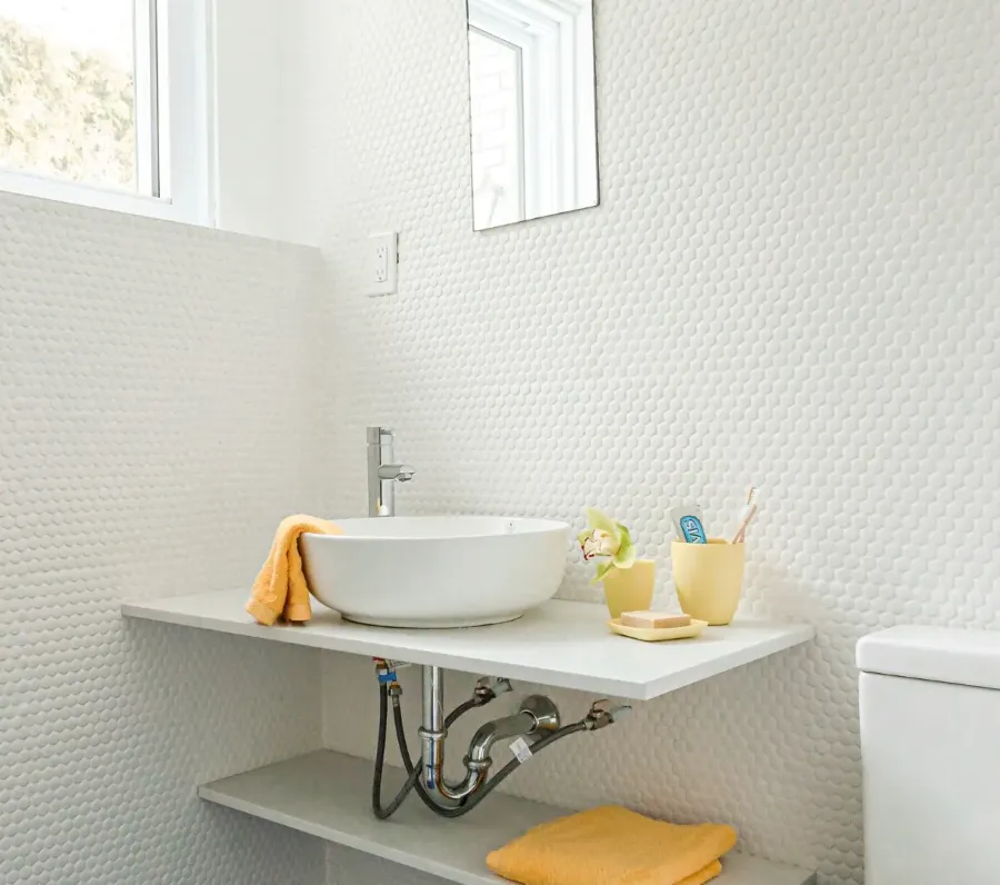 Salle de bain du sous-sol dans la rénovation du bungalow de Montréal — compacte, tapissée de pierre, à l'éclairage chaleureux.