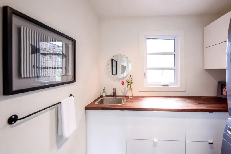 Salle de lavage du cottage de Montréal — électroménagers intégrés derrière des panneaux sur mesure.