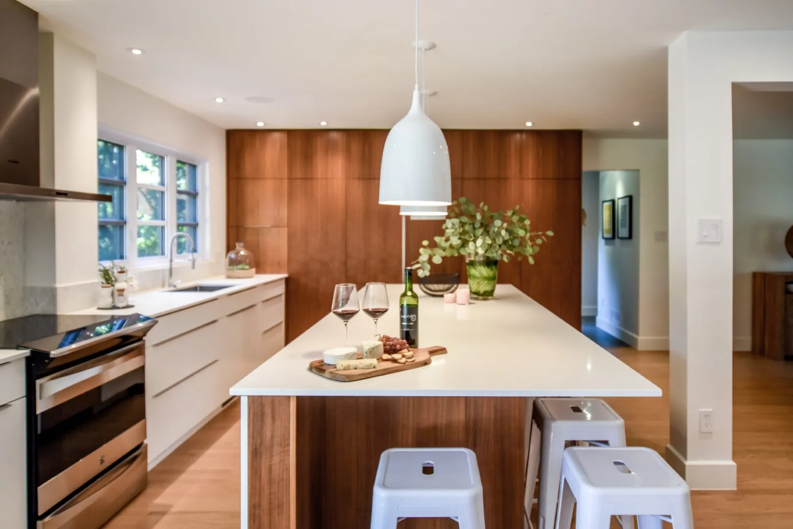 Cuisine du cottage de Montréal — ébénisterie blanche et accent de noyer, réfrigérateur intégré derrière des panneaux.