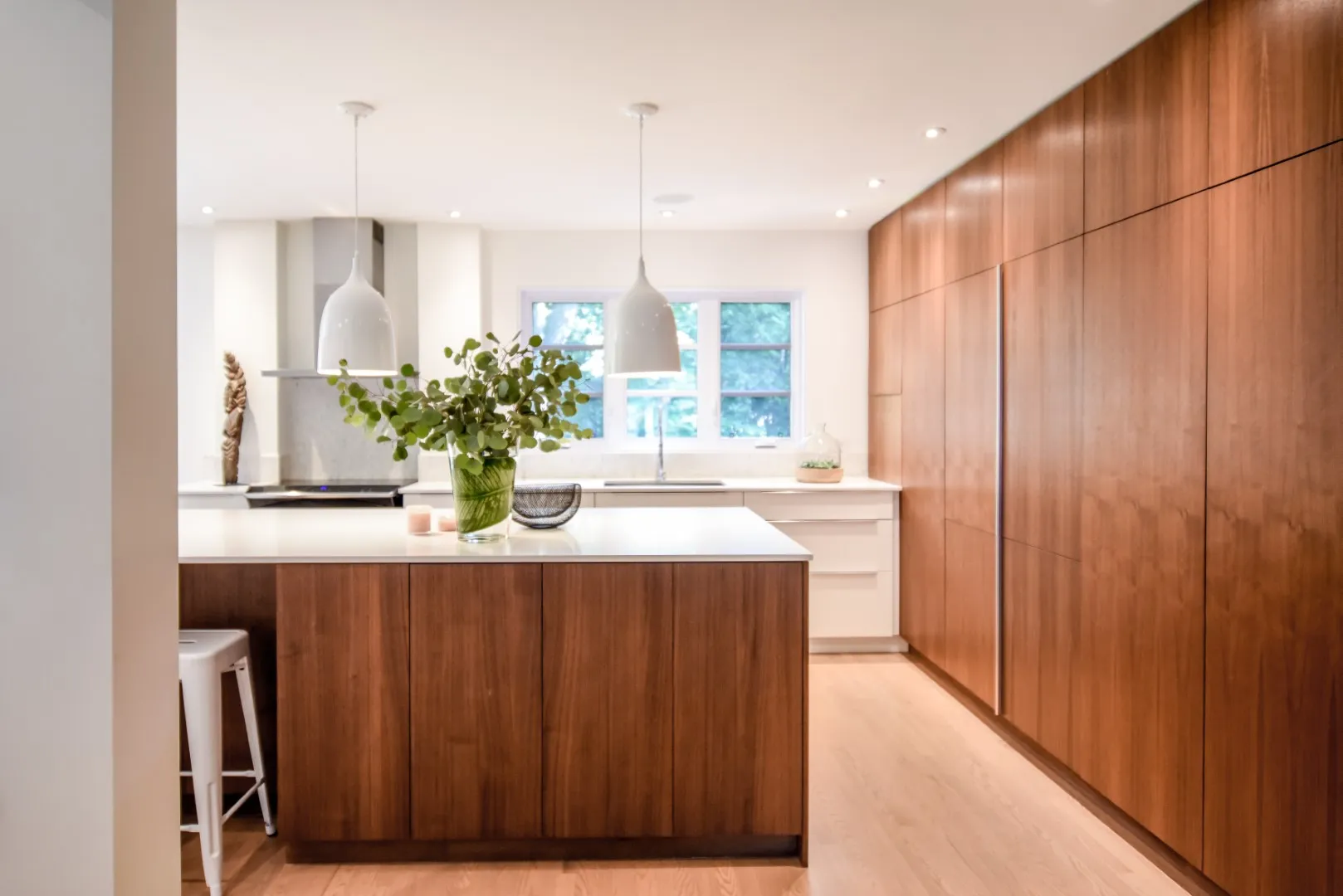 Vue large de la cuisine — comptoir pâle et îlot en noyer, cottage de Montréal.