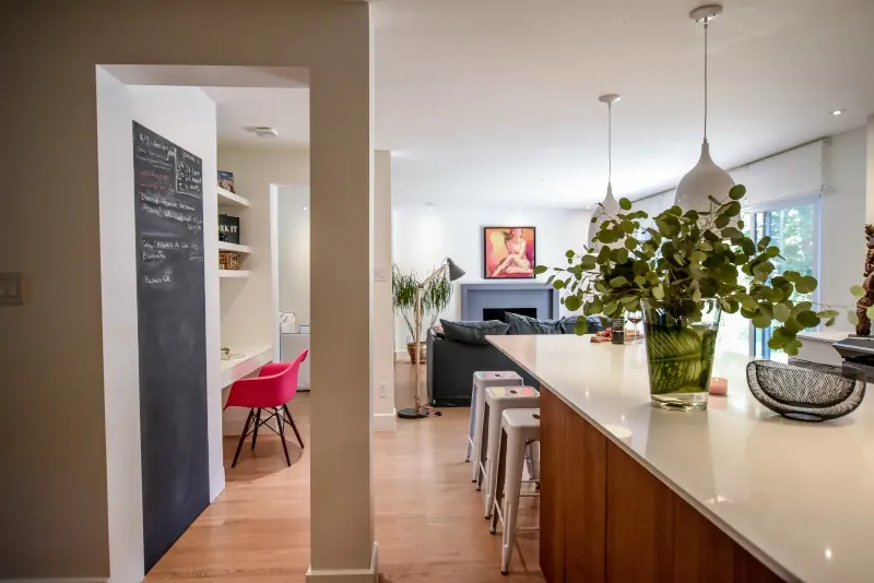 Cuisine familiale ouverte sur l'aire de vie — îlot habillé de noyer et comptoir blanc, cottage de Montréal.